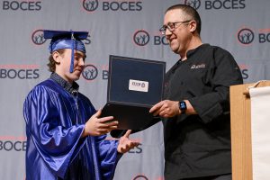 A CTE student is receiving his diploma during the graduation ceremony.