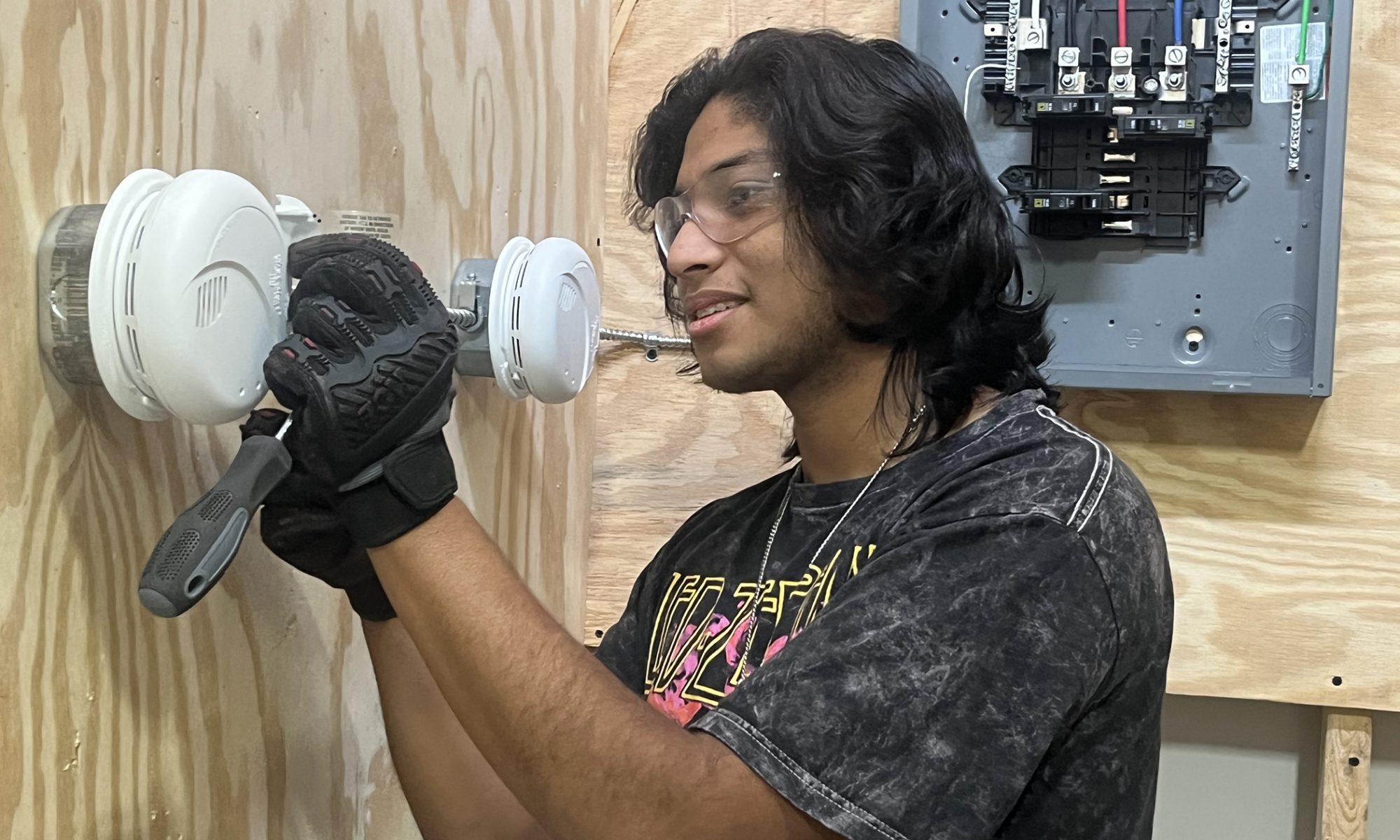 A student works on wiring a smoke detector during a lesson inside the classroom setting.