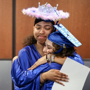 Two graduates embrace in a hug.