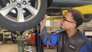 Auto service student working on a car that is on a lift