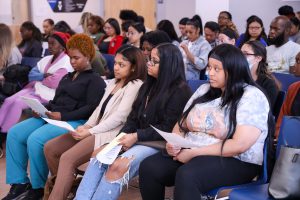 A group of students sitting in chairs are listening to a presentation.