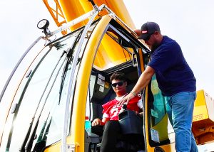 student sits in crane cab as National Grid employee explains the equipment 