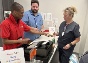 Retail student helps a customer as a TA looks on