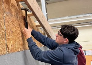 Student hammering a shed wall