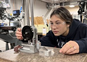 Student adjusts a gauge on a machine