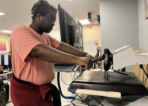 A student uses a logo press in digital media