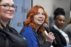 A student spoeeks into the microphone while smiling