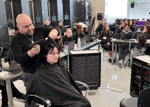 Hair stylist putting on a demo in front of students