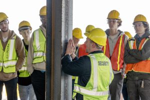 Teacher in front of a beam with studebts