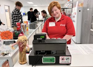 Student standing behind a cash register smiling