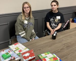 Two female students pose at a wrapping table