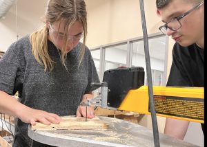 Student using a table saw as another student looks on