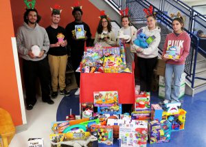 Students with toys in front of a winter sled packed with toys