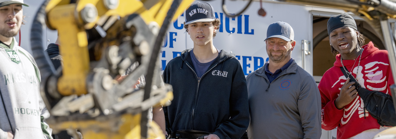 Welding students in protective clothing work together on a project.