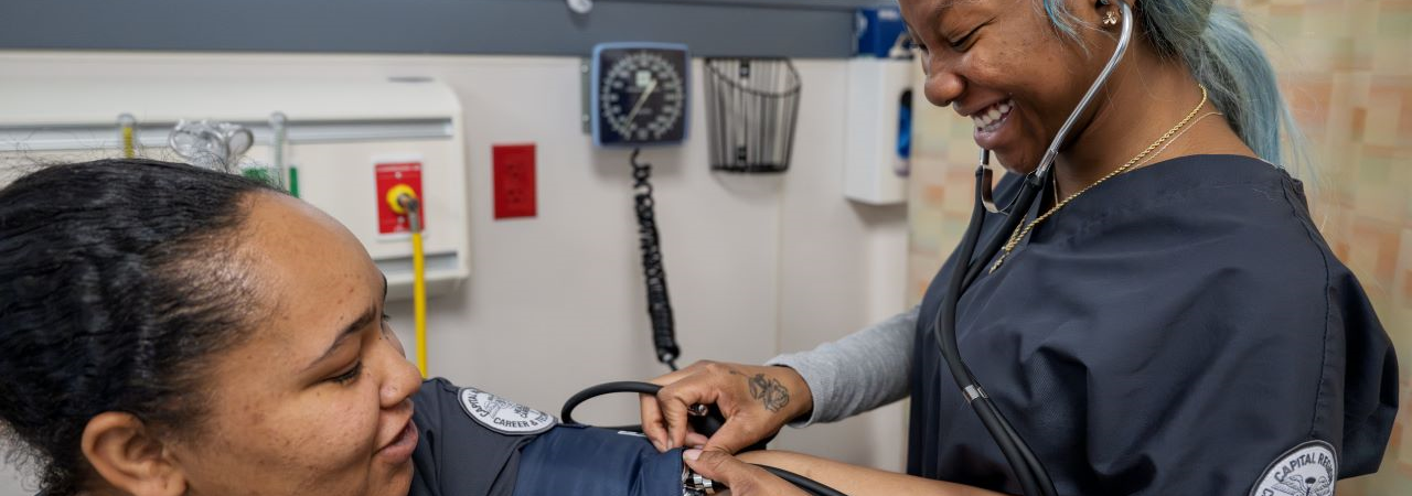 Nursing student taking blood pressure on patient.