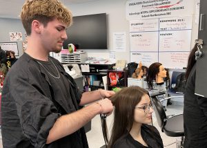 A male student curls hair on a female student