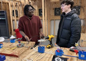 A current student and a prospective student talk and smile in the electrical lab