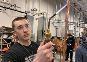 A student solders a copper pipe