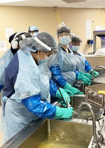 Sterile student in PPE cleaning instruments at Albany Med