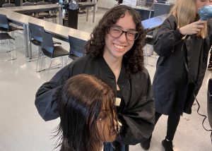 A student smiles while styling hair