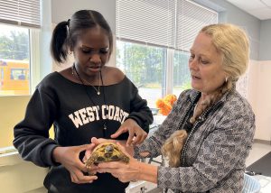 A student and teacher hold a tortoise