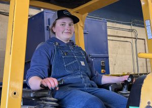 Female student sits in the seat of a dozer